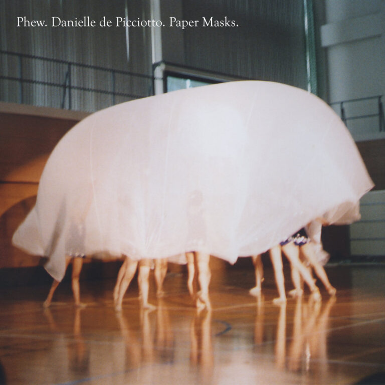 Mehrere Körper bewegen sich unter einem großen, halbtransparenten Schleier in einer Halle, Beine sichtbar, Titel Paper Masks von Phew und Danielle de Picciotto oben eingeblendet.