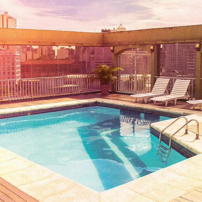Dachterrassenpool im warmen Sonnenlicht vor urbaner Skyline, retroästhetische Farbstimmung mit Liegestühlen und Betonarchitektur.