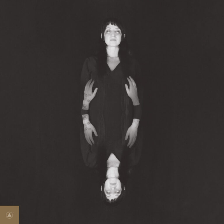 Ein quadratisches Albumcover in Schwarz-Weiß zeigt die Künstlerin Ora Cogan in einer vertikalen Spiegelung. Oben steht sie aufrecht vor schwarzem Hintergrund, unten erscheint ihr Abbild kopfstehend. Ihre langen dunklen Haare und ein dunkles Kleid verschmelzen mit der Dunkelheit. In der Mitte des Bildes ragen vier tätowierte Hände aus dem Schatten hervor, die ihren Körper flankieren.