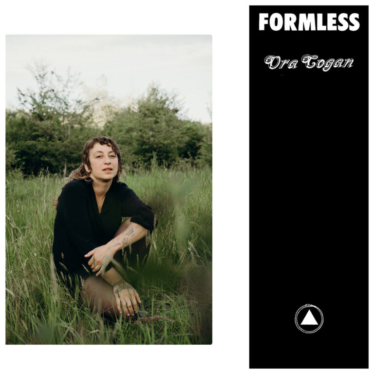 Das Bild ist zweigeteilt: Links hockt Ora Cogan mit tätowierten Armen sowie melancholischem Blick in einer hohen, grünen Wiese vor einem Waldhintergrund. Rechts befindet sich ein schwarzer Balken mit dem Albumtitel „FORMLESS“, dem Künstlernamen in geschwungener Schrift sowie einem kreisförmigen Logo mit einem Dreieck am unteren Rand.
