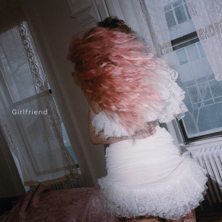 Das Albumcover zeigt Grace Ives von hinten mit voluminösem, lockigem Haar in einem kräftigen Rosaton, das über ein weißes, gerüschtes Spitzenkleid fällt. Sie befindet sich in einem hellen Raum mit Spitzenvorhängen und einem Heizkörper, wobei der Fokus auf der Textur ihres Haares und der Kleidung liegt.