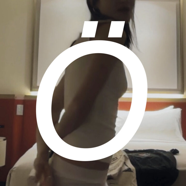 Ein quadratisches Bild zeigt eine junge Frau in einem hellen Tanktop in einem leicht unterbelichteten Raum vor einem Bett. Über das gesamte Motiv ist ein großes, weißes, minimalistisches „Ö“ gelegt, das den Körper der Person teilweise verdeckt und als zentrales grafisches Element fungiert.