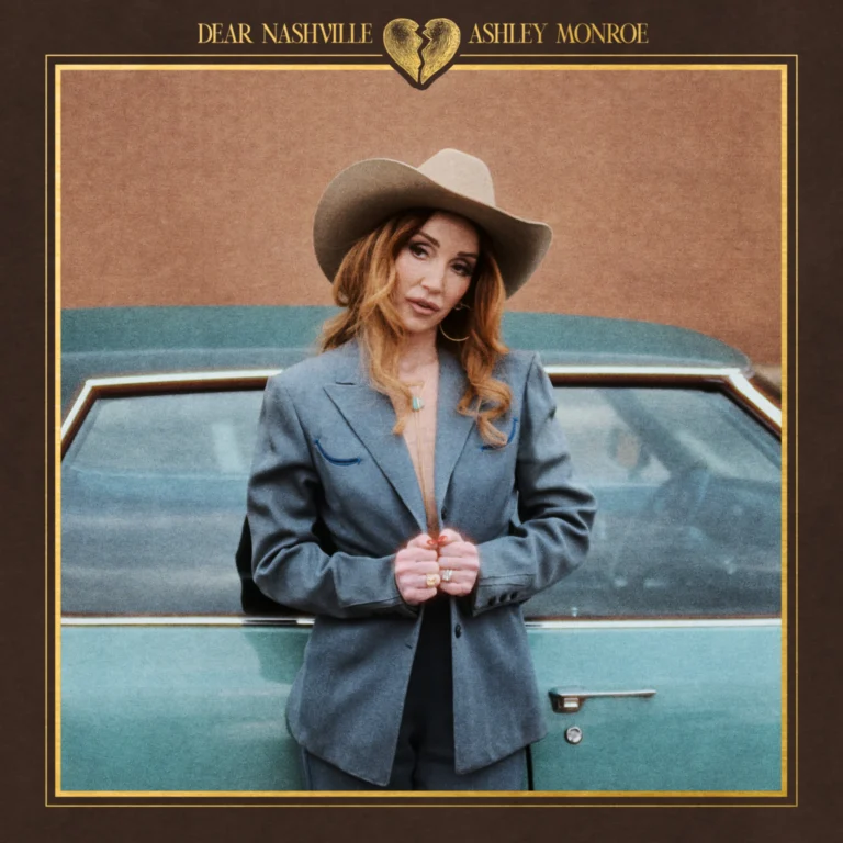 Nahaufnahme von Ashley Monroe vor einem neutralen Hintergrund, ihr Blick ist direkt und ungeschminkt, was eine Atmosphäre von Aufrichtigkeit und Melancholie erzeugt.