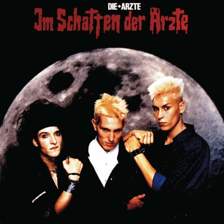 Drei junge Männer posieren in einer dramatisch inszenierten Studioumgebung mit kontrastreichem Licht und Schatten, wobei ihre Gesichter eine Mischung aus Ernsthaftigkeit und jugendlicher Pose zeigen.