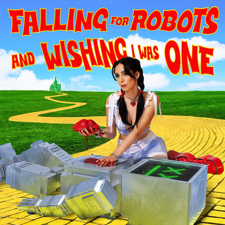 Das Bild zeigt die Musikerin LØLØ in einer Dorothy-ähnlichen Inszenierung auf einem gelben Ziegelweg in einer grünen Landschaft unter blauem Himmel. Sie kniet über den silbernen Einzelteilen eines Roboters und hält ein blutendes, anatomisches Herz in der Hand, während ihre Finger und die Oberfläche des Roboters mit Blut verschmiert sind.