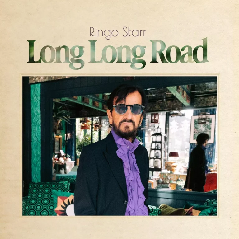 Das quadratische Albumcover zeigt im oberen Drittel den Schriftzug „Ringo Starr“ in feiner Serifenschrift und darunter den Albumtitel „Long Long Road“ in großen, dunkelgrünen Buchstaben vor einem beigefarbenen Hintergrund. Im Zentrum befindet sich ein gerahmtes Foto des Künstlers, der ein dunkles Sakko über einem auffälligen lila Rüschenhemd trägt und eine dunkle Sonnenbrille aufhat. Er steht vor einer tiefenunschärf hergerichteten Kulisse mit grünen Wandelementen, gemusterten Kissen und asiatisch anmutenden Dekorationsgegenständen.