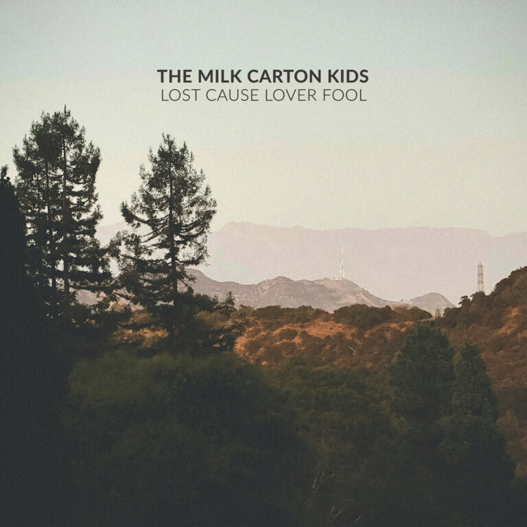 Ein quadratisches Albumcover zeigt eine hügelige Landschaft im Stil einer analogen Fotografie mit entsättigten Farben. Im Vordergrund stehen dunkle, schattenhafte Nadelbäume. Im Hintergrund erheben sich blasse, violett-graue Berge unter einem dunstigen, hellen Himmel. Inmitten der Hügel sind zwei dünne Funkmasten zu erkennen. Am oberen Rand steht in schlichten, schwarzen Großbuchstaben der Name der Band und darunter der Albumtitel.