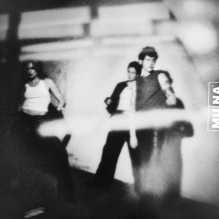 Ein quadratisches Albumcover in körnigem Schwarz-Weiß. Es zeigt drei Personen in einer unscharfen, fast geisterhaften Bewegung vor einem architektonischen Hintergrund mit harten Schatten. Ein breiter, heller Lichtstreifen zieht sich horizontal durch das untere Drittel des Bildes und überlagert die Beine der Figuren. Am rechten Rand steht vertikal der Schriftzug MUNA in einem schmalen Rahmen.