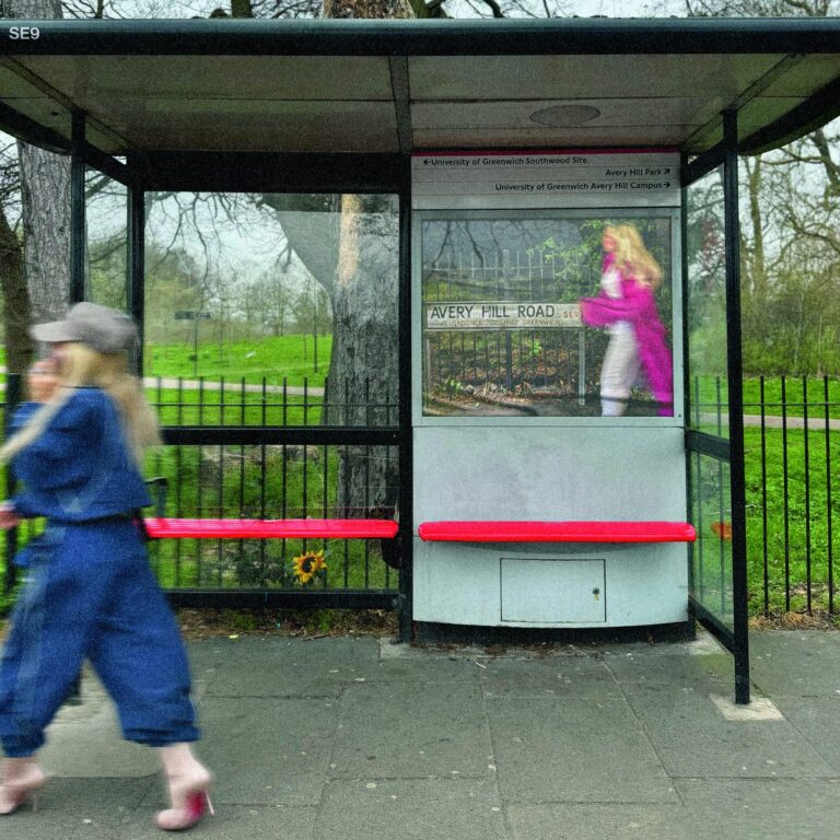 Eine verschwommene Person geht an einem Londoner Bushaltestellenhäuschen vorbei, in dem ein Plakat hängt.