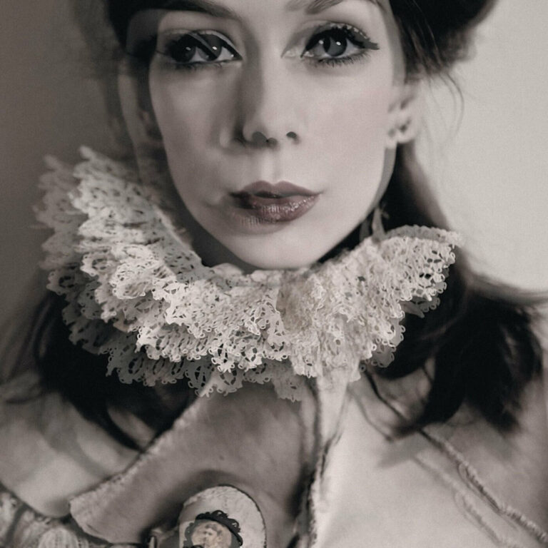 Porträt einer Frau mit historischer Spitzenkrause und dunklem Augen-Makeup.