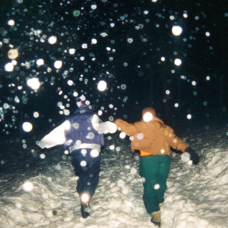 Zwei Personen rennen nachts im Schneegestöber von der Kamera weg.