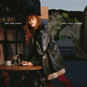 Carly Rae Jepsen lehnt im Trenchcoat vor einem Café an einem Bistrotisch.