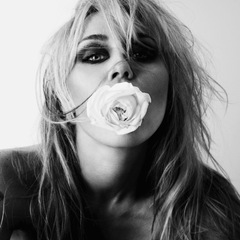 Schwarz-Weiß-Aufnahme von Miley Cyrus mit einer weißen Rose zwischen den Lippen.